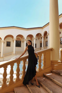 Black turtle neck Dress with ruffles and high/low skirt on stairs.